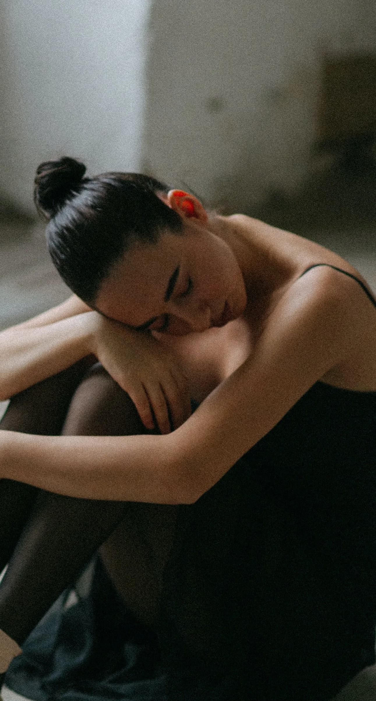 woman hugs her knees representing symptoms of pmdd
